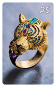 25 Der Ring im Magic Cat Lenormand. Es ist ein goldener Ring mit bunten Edelsteinen in Form eines Löwenkopfs zu sehen.