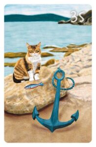 35 Der Anker im Magic Cat Lenormand. Es ist eine Katze an einem Strand zu sehen, die vor sich einen Fisch liegen hat. Davor befindet sich großer Schiffsanker.